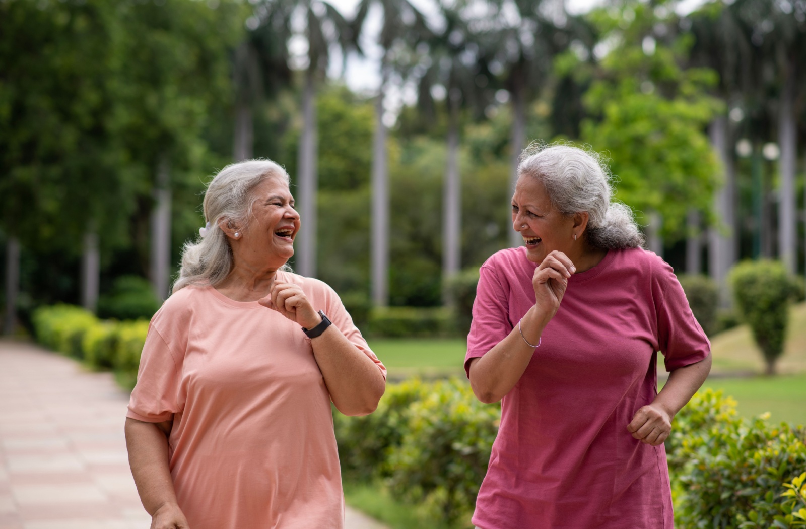 Two senior women walking together outdoors to help manage osteoporosis.
