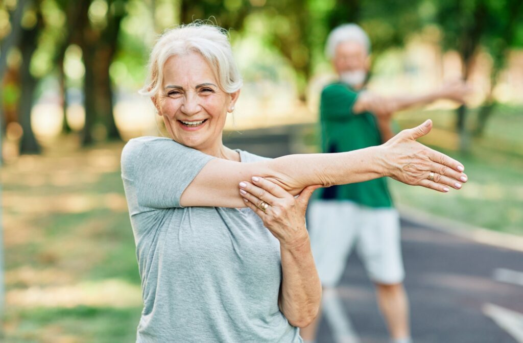  A senior woman stretching before exercising outdoors with a group.