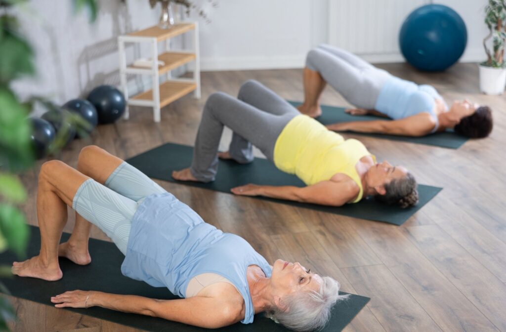  A group of seniors exercises by performing a bridge pose on yoga mats.