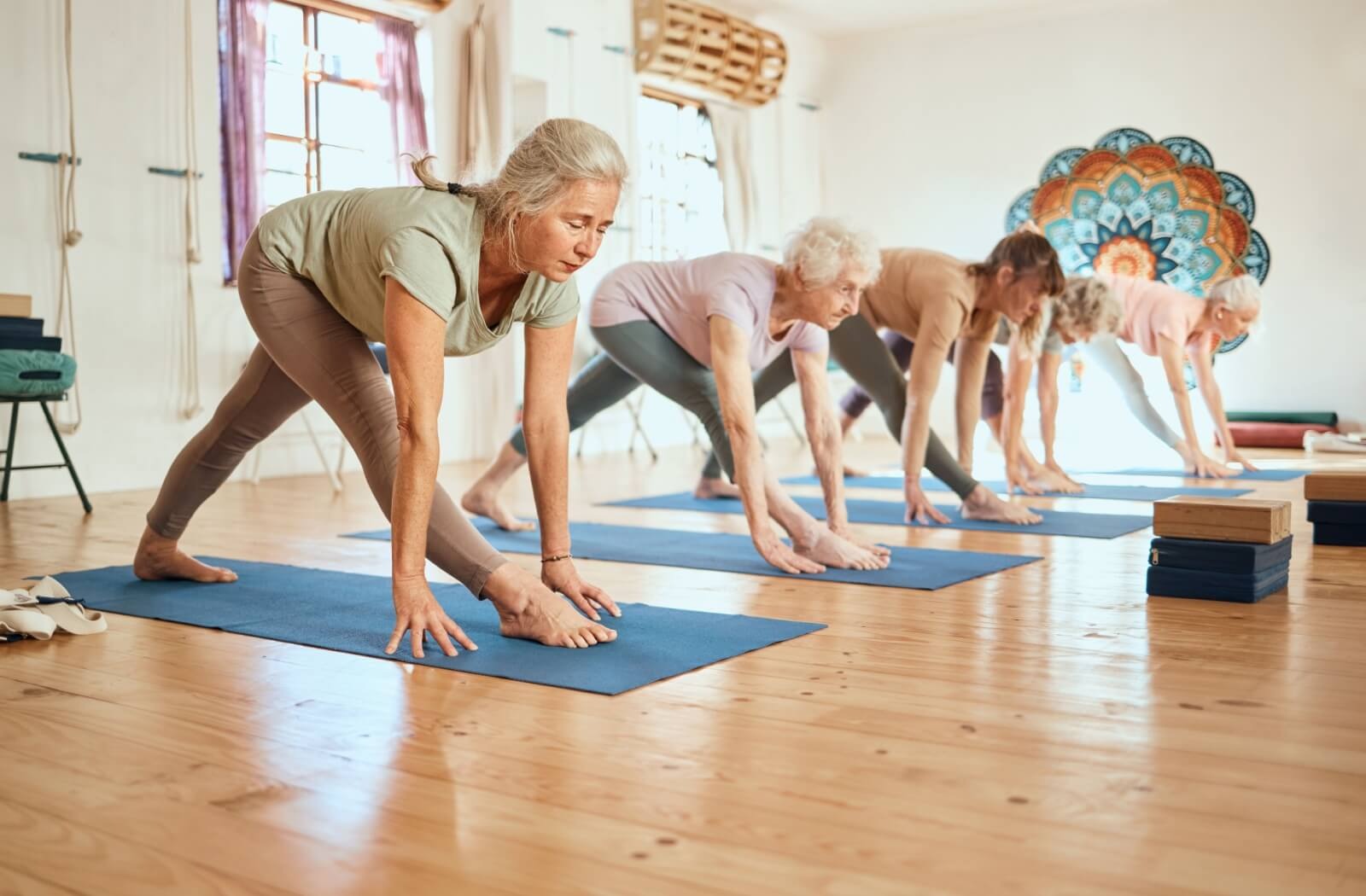 : A group of seniors practice yoga poses in a bright studio.